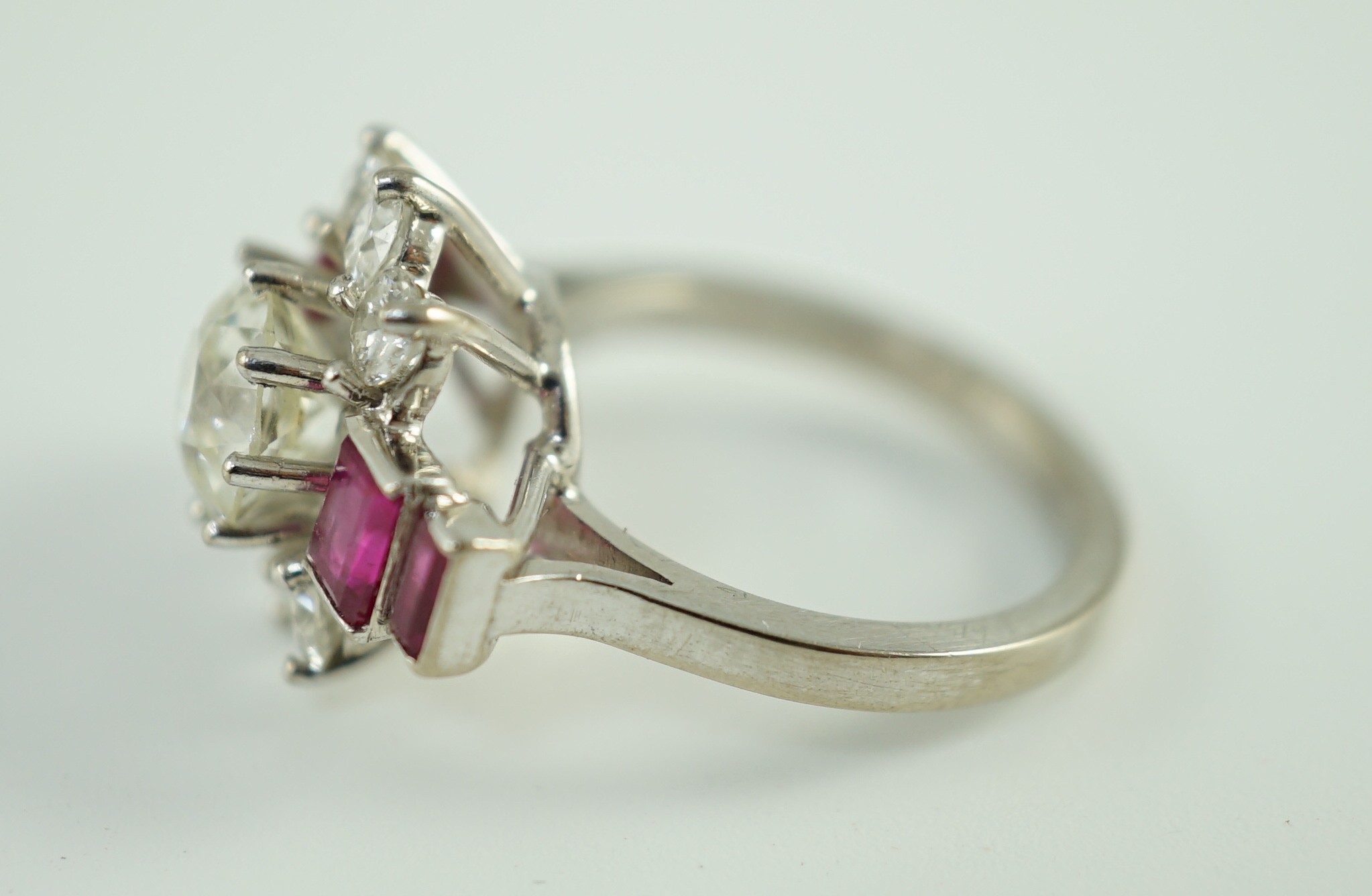 A platinum and single stone diamond dress ring, bordered by six round cut diamond and each shoulder set with two graduated rectangular rubies